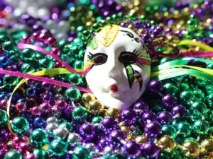 A white face mask on colorful beads during the Mardi Gras carnival celebration